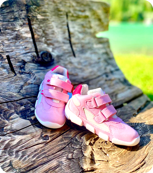 Hochwertige pinke Kinderschuhe mit Klettverschluss auf einem rustikalen Holzstamm – Perfekt für stilvolle und bequeme Schritte. Jetzt im Online-Shop entdecken!